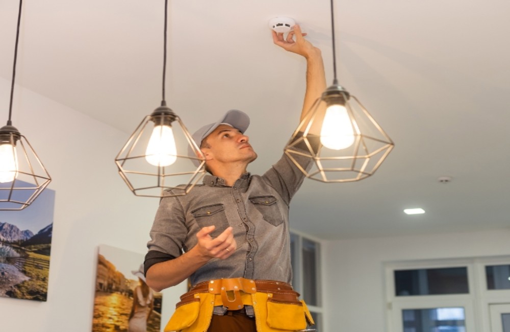 Technician fixing smoke alarm